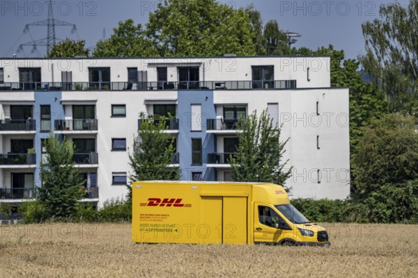 DHL parcel van, electric vehicle, on the way to a customer, rural, driving along a dirt track
