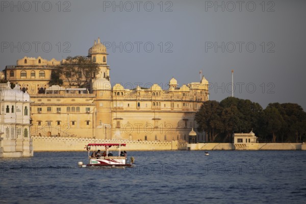Excursion boat on Lake Pichola, behind the City Palace in the evening light, Udaipur, Rajasthan,