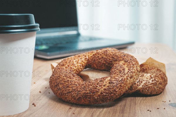 Simits with coffee on a wooden table, with a laptop, in a cozy working environment, snack,