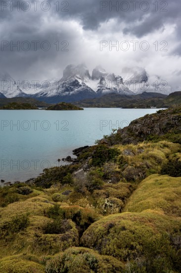 Cloudy mountain range Cuernos del Paine, shore of the blue lake Lago Pehoe in the evening light,