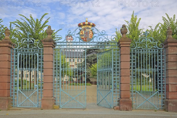 Gate entrance with metal gate, decorations and coat of arms, white tower, wrought ironwork,