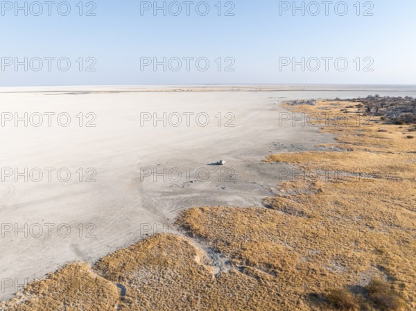Rocky island with baobab trees in a dry salt pan, off-road vehicle on the salt pan, aerial view,