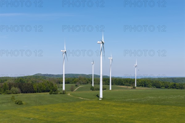 Wind turbines on a green field surrounded by forest under a blue sky, Swabian Alb,