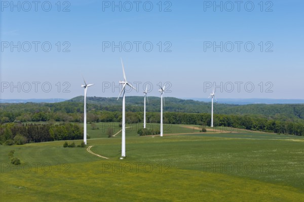 Several wind turbines on extensive meadows with forest in the background, Swabian Alb,