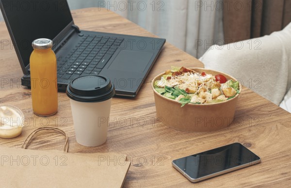 Work at home on a laptop, there is food on the table, salad, coffee and juice, delivery, there are