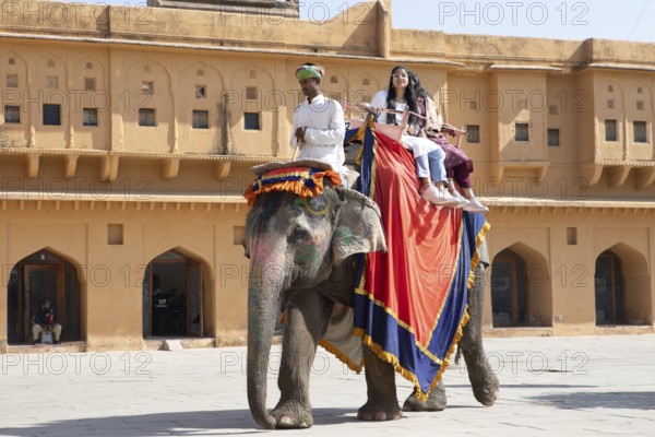 Indian mahout and Indian woman riding a colourfully painted elephant at the Amber Fort or fortress,
