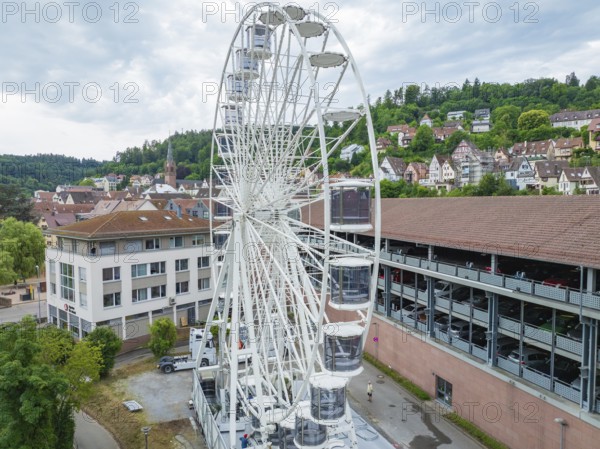 A large Ferris wheel in the middle of an urban environment with a cloudy sky, Ferris wheel