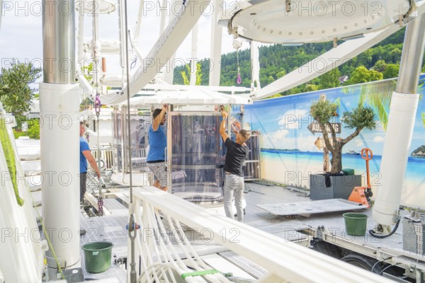 People aligning a cabin in a Ferris wheel in front of a landscape scenery, Ferris wheel