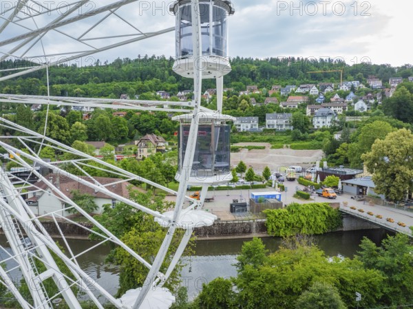 Panoramic view from the Ferris wheel of the river, town and green hills under a cloudy sky, Ferris