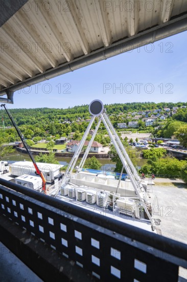 A Ferris wheel seen from above, surrounded by green landscape and buildings, Ferris wheel