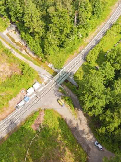 A railway crossing in the middle of a forest with several roads and vehicles, construction of the