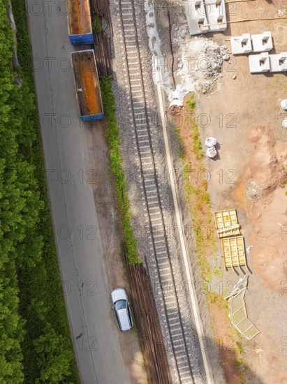 Aerial view of railway tracks and construction work, with a passing car, construction of the