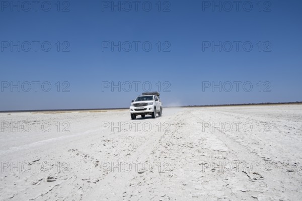 Off-road vehicle driving on a wide empty salt pan, Makgadikgadi Salt Pans, Botswana