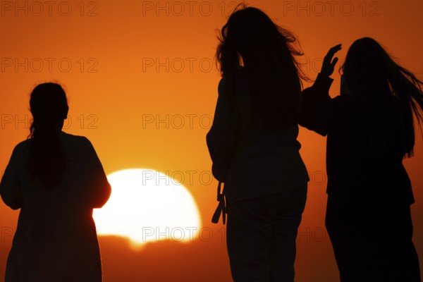 People watching the sun set on the horizon from the summit of the Großer Feldberg in the Taunus,