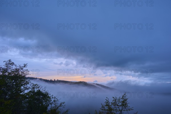 Landscape with rolling hills and trees in the mist as the sun rises, summer, Rhine bend Boppard,