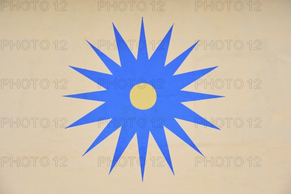 Blue stylised star with yellow centre on beige background, Rüdesheim am Rhein, Rhine Valley,