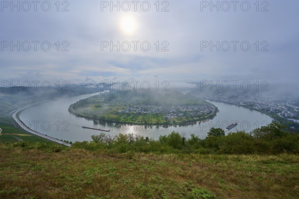 River with bend and cargo ship in the morning fog with light cloudy sky, summer, Rhine bend