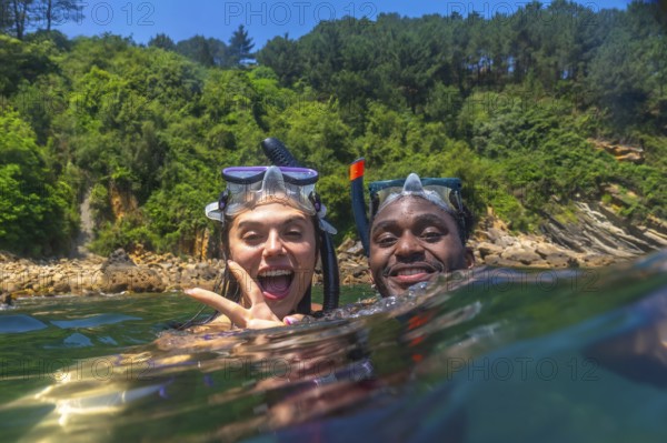Interracial couple snorkeling together in the vibrant ocean, enjoying a fun filled summer vacation