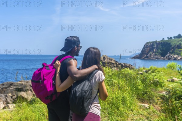 Couple savoring a stunning ocean view during a summer hike, celebrating the beauty of nature and