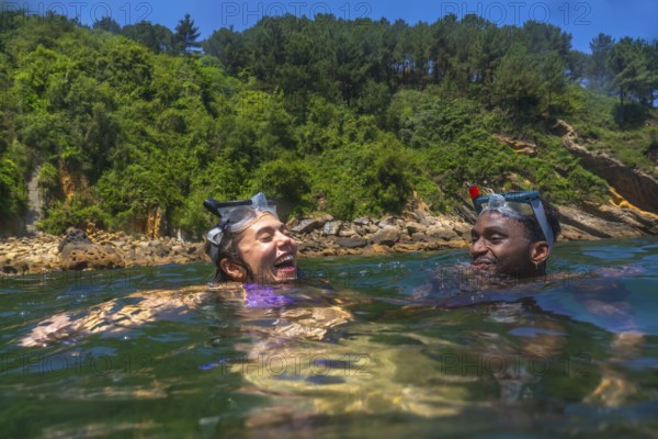 Tourists wearing snorkeling masks, laughing joyfully while enjoying a sunny summer vacation in the
