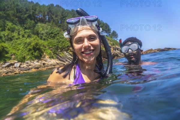 Happy couple snorkeling together in the ocean near the rocky coastline, enjoying their summer