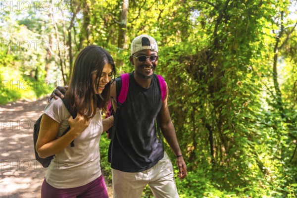 Happy couple hiking together, enjoying a scenic walk along a lush green forest trail, surrounded by
