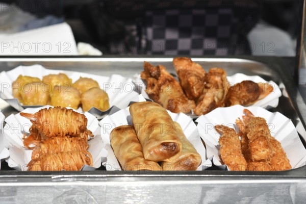 Different small fried Thai street food snacks like fried shrimp, springrolls or potato noodle