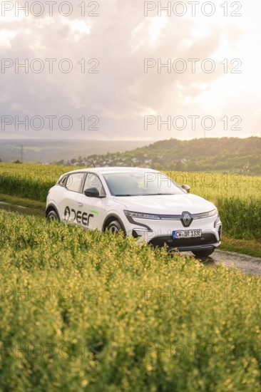 Car next to a field in a hilly landscape at sunset, Deer E- CarSharing, Renault Megane electric
