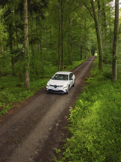 Car on a green forest path, surrounded by dense forest, Deer E- CarSharing, Renault Megane electric