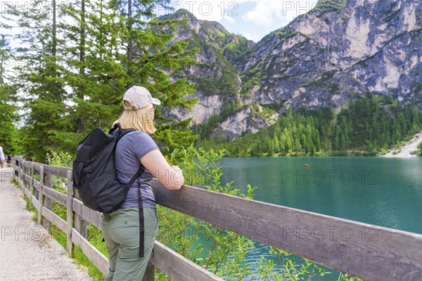 Person looking from a wooden fence at a mountain lake, surrounded by nature, Lake Braies, South