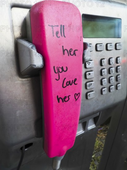 Telephone receiver of a Telekom payphone with the inscription Tell her you love her in Wuppertal,