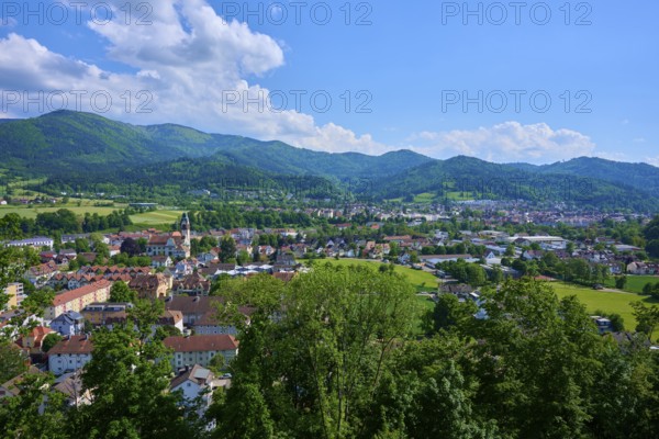 View of a district town surrounded by green hills under a cloudy blue sky, Waldkirch, Breisgau,