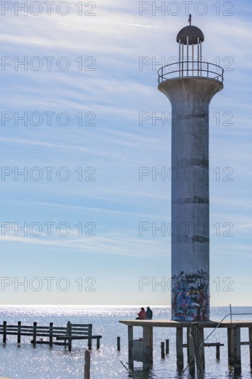 Man and woman sitting on a concrete platform at the base of the graffiti, covered Broadwater Beach
