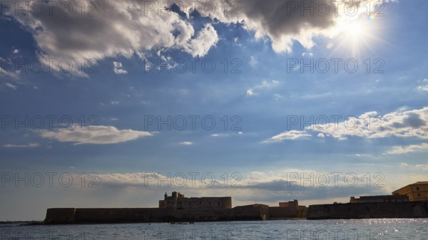 Castello Maniace, sea fortress Maniace, coastal fortress in sunlight under a cloudy sky, boat trip