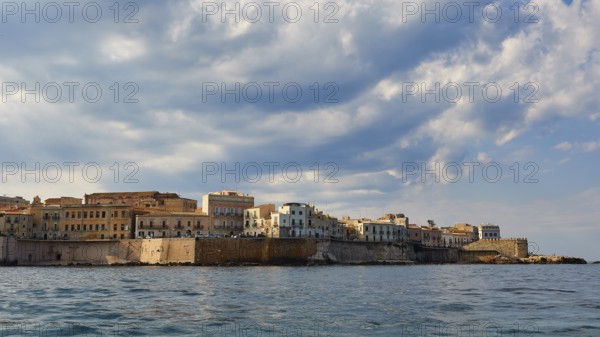 City along the coast with high clouds on the horizon, boat trip around the island of Ortigia, Isola