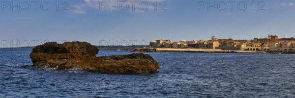 Coastal cliffs in the foreground with a town and blue sky in the background, boat trip around the