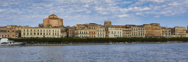 Coastal view with historic buildings against a cloudy blue sky on the promenade, boat trip around