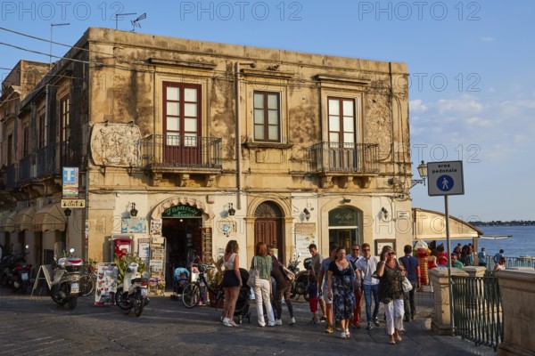 Lively streets with shops and views of the sea, surrounded by old town architecture, Ortigia