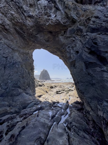 Large rock with a hole and people in the foreground, Hole in The Wall, Rialto Beach, Olympic