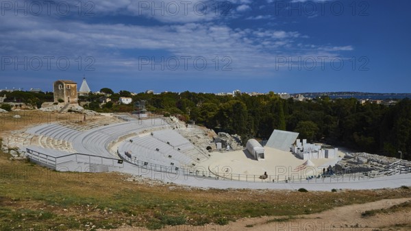 Greek amphitheatre, view of a large ancient amphitheatre with surrounding nature and blue sky with