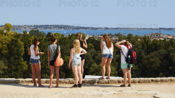 Group of young people looking at a landscape with sea and trees on a sunny day, Neapolis