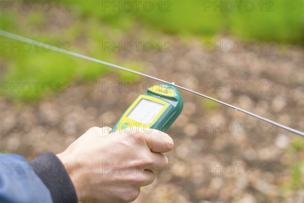 Hands holding a device for an electrical measurement on a wire, Waldweide Gechingen, compensation