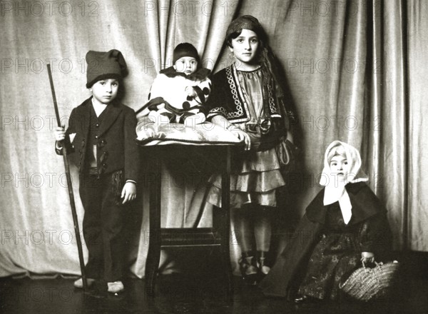 Children dressed up, 1910s, Four children in traditional costumes in front of a curtain, Group