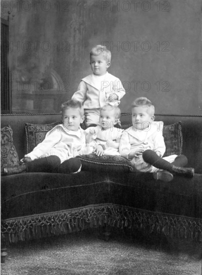 Small children sitting on sofa, 1930s, Four children in classic clothes sitting together on a couch