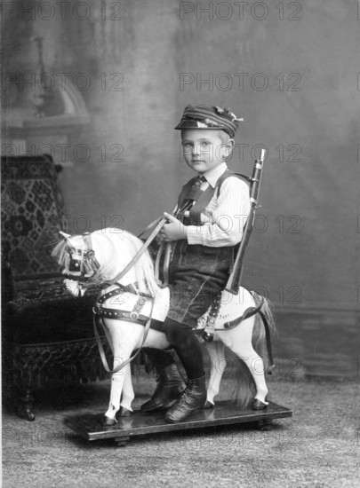 Little boy sitting on a rocking horse, 1910s, Boy in traditional clothing riding a wooden rocking