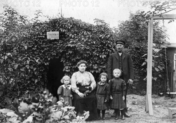 Family photo in the garden, 1930s, Family portrait with parents and three children in front of a
