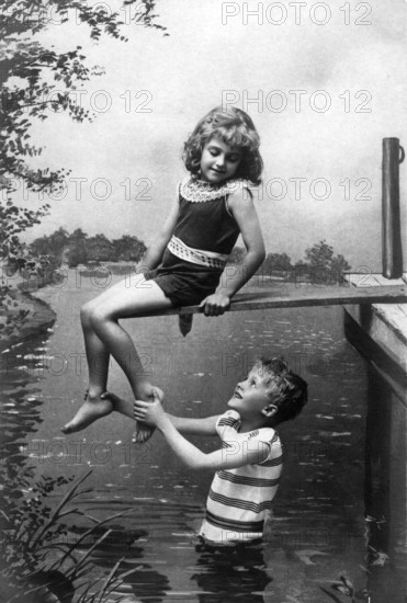 Boy holding girl by the foot, 1920, A boy happily lifting a girl, both in swimwear enjoying the