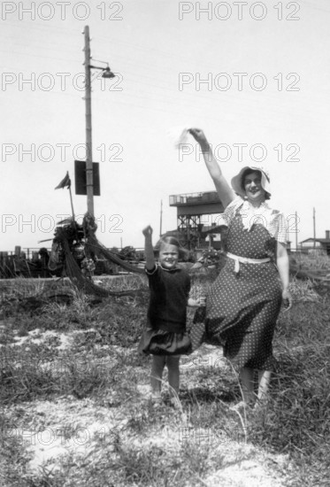 Woman and child saying goodbye, 1930s, Woman and child raising their hands in the air in greeting,