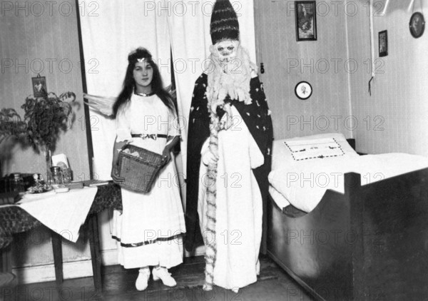 Christmas angels and St Nicholas, 1930s, A dressed-up couple stands in a festively decorated room,