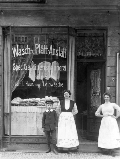 Washing and plating shop ca. 1915, woman and a boy in front of an antique shop with a window